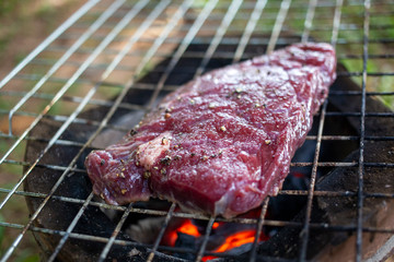 Raw beef steak with seasoning such as salt and black pepper grilling on charcoal stove. Homemade cooking beef steak local style recipe's.