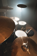 Modern Drum Set Prepared For Playing In A Dark Rehearsal Room On Stage With A Bright Spotlight. The Concept Of Percussion Musical Instruments Of All Musical Directions