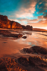 Canvas Print - Waves washing over rocks at beach with cliffs in background