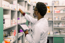 African American Male Pharmacist Using Digital Tablet During Inventory In Pharmacy.