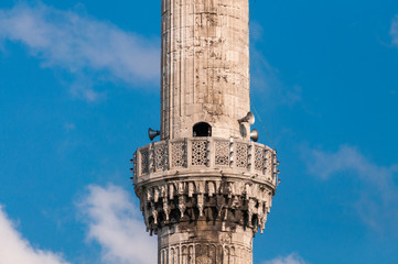 Minaret tower with megaphones attached against blue sky on the background