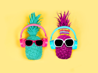 Pineapples in headphones and glasses on a yellow background