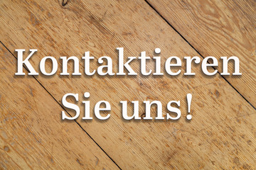 Wall Mural - `kontaktieren sie uns` white text on a wooden home background. translation: `contact us`