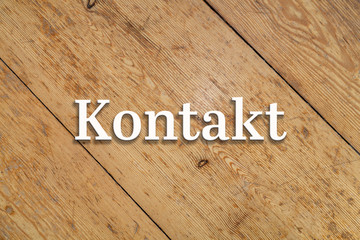 Wall Mural - `Kontakt` white text on a wooden background. Translation: `Contact`