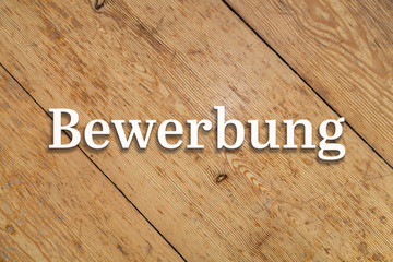 Wall Mural - `bewerbung` white text on a wooden home background. translation: `application`
