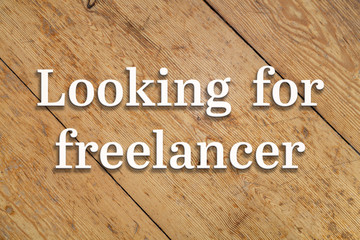 Wall Mural - `looking for a freelancer` white text on a wooden background.