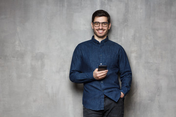 Poster - Man standing with cellphone in hands, isolated on grey background