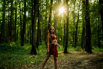 Wall Mural - Enjoying her beauty. ethnic tribal fashion. deep forest. sexy girl in leather suede clothes. cougar female. amazon woman. sexy witch. wild woman in forest. female silhouette through the sun rays