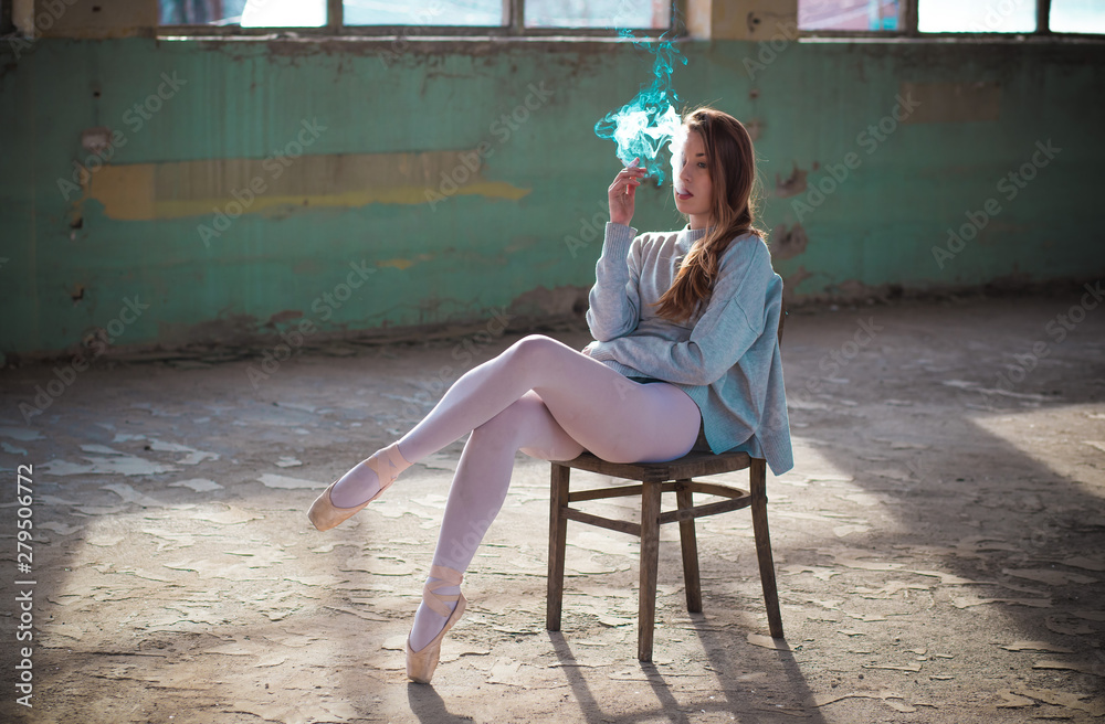 Ginger, blonde ballerina sitting on the chair smoking. Sport and smoking  concept Stock Photo