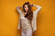 © bestsenny - Young woman with long hair looks at the camera with her hands up to the head, yellow background