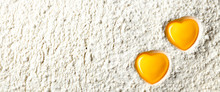 Two Yellow Heart Shaped Egg Yolks On White Flour Background - Love To Bake Concept