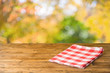 © maglara - Empty wooden table with tablecloth over autumn nature park background