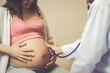 © InfiniteFlow - Happy pregnant woman visit gynecologist doctor at hospital or medical clinic for pregnancy consultant. Doctor examine pregnant belly for baby and mother healthcare check up. Gynecology concept.