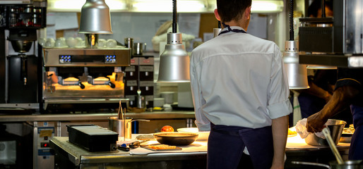 Head chef in a commercial kitchen with another chef preparing a meal