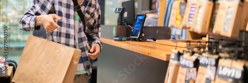 Fotomural young man making a purchase and paying at the cash deck in the store