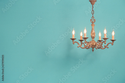 Fotografía Retro antique old bronze chandelier with bulb lamps shaped candles hanging front mint blue wall background