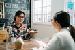 © PR Image Factory - asian young girl talks about her experience for job interview in cafe bar. back view of lady hr manager taking reading resume and candidate answer question. job seeker interviewer meet in coffee shop
