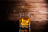 Fototapeta Tulipany - Glasss of whiskey with ice cubes on wooden background