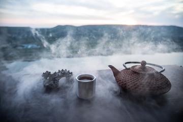 Tea concept. Japanese tea ceremony culture east beverage. Teapot and cups on table with bamboo leaves on sunset