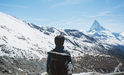 Wall Mural - a man with backpack looking at swiss alps, matterhorn mountain landscape in zermatt, switzerland