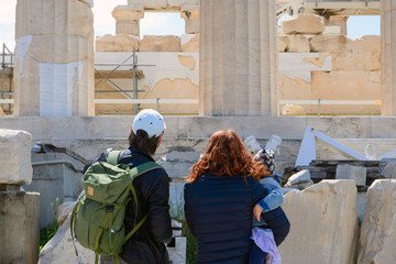 a man and a woman with a little girl in their arms consider the ruins of the temple. ancient greek r