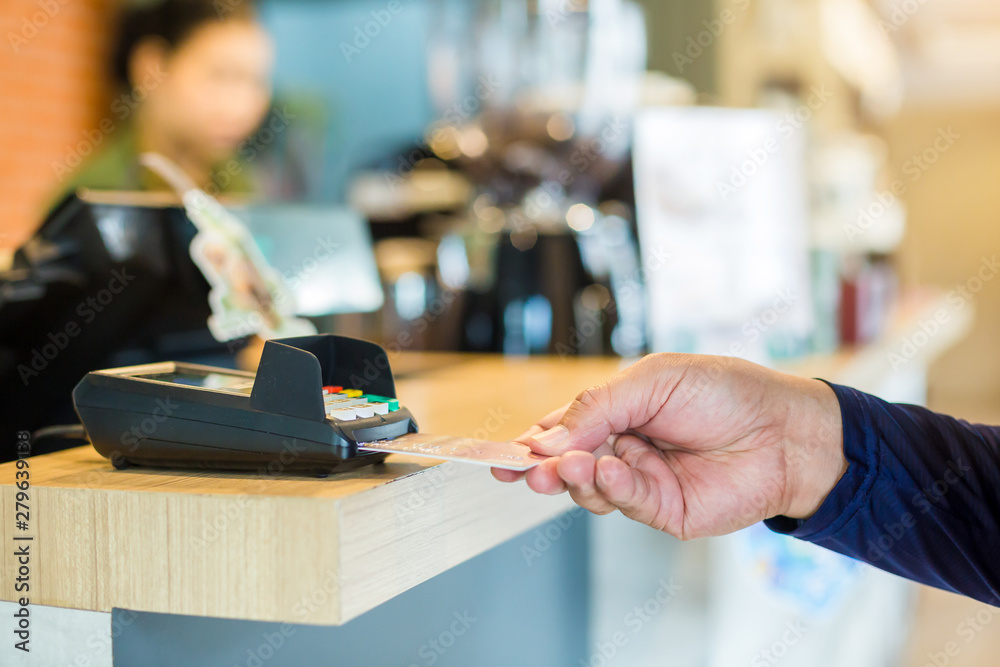 Hand put credit card In slot of credit card reader with blurry cashier at  counter service,