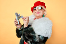 Happy Old Stylish Woman In Sunglasses Boasting Her Money. Isolated Yellow Background, Studio Shot, Fashion, Style
