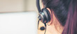 Back view of woman consultant wearing microphone headset of customer support phone operator at workplace. proportion of the banner for ads.