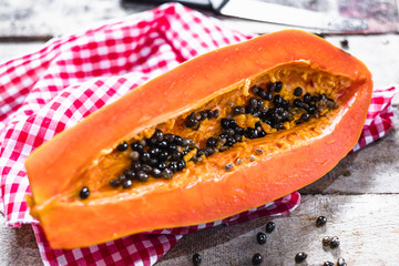 Half of ripe papaya with seeds on old wooden plank background.