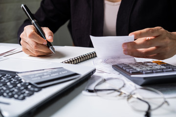 Stressed young woman checking bills, taxes, bank account balance and calculating expenses in the living room at home