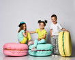 © FAB.1 - Three friends of triplets - two girls and a boy in bright clothes have fun at the birthday party fun room decoration candy macarons
