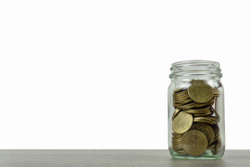 Wall Mural - Savings and investment concepts. Stack of coins in a glass jar on wooden table isolated on white background and space.