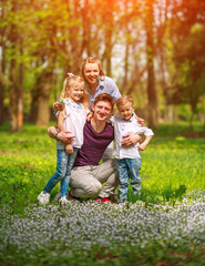 Wall Mural - Portrait of family having fun in flowering city park on bright sunny day happily spending their leisure time together outdoors