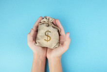 Women Hold A Money Bag On Blue Background, Saving Money For Future Investment Concept.