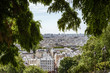 Montmartre: tourists and view over Paris rooftops framed by foliage