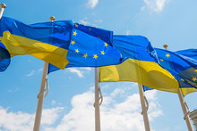 Row Of Flag Poles With European Union And Ukraine Flags Fluttering By Wind On Blue Sky Background