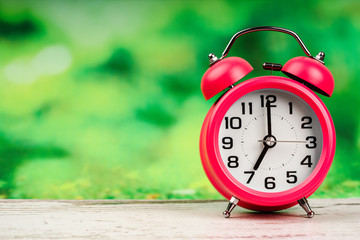 alarm clock on wooden and green background