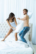 © opolja - Happy young couple is having fun in bed. Enjoying the company of each other. Pillow battle.