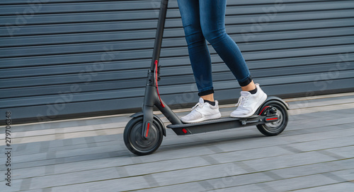 фотография  Close up of woman riding black electric kick scooter at cityscape, motion blur