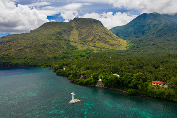 Wall Mural - Aerial view of a large cross marking a sunken cemetery off the tropical, volcanic island of Camiguin