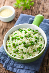Wall Mural - Fresh homemade creamy green pea risotto in green bowl, grated cheese in the back (Selective Focus, Focus one third into the risotto)