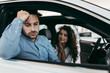 © Dusko - Worried middle age man with his wife buying car in auto salon or showroom. He is hipped while woman asks him to still buy a car.