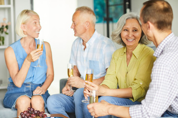 Wall Mural - Group of cheerful senior people enjoying champagne during party at home, copy space