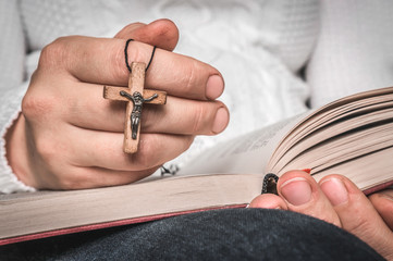 Christian woman with wooden cross reading a holy Bible