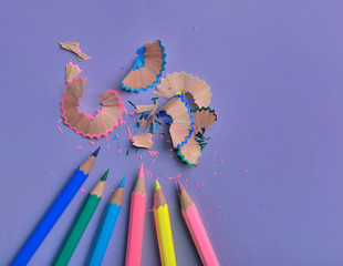 close on wooden colorful pencils sharpened on colored paper background