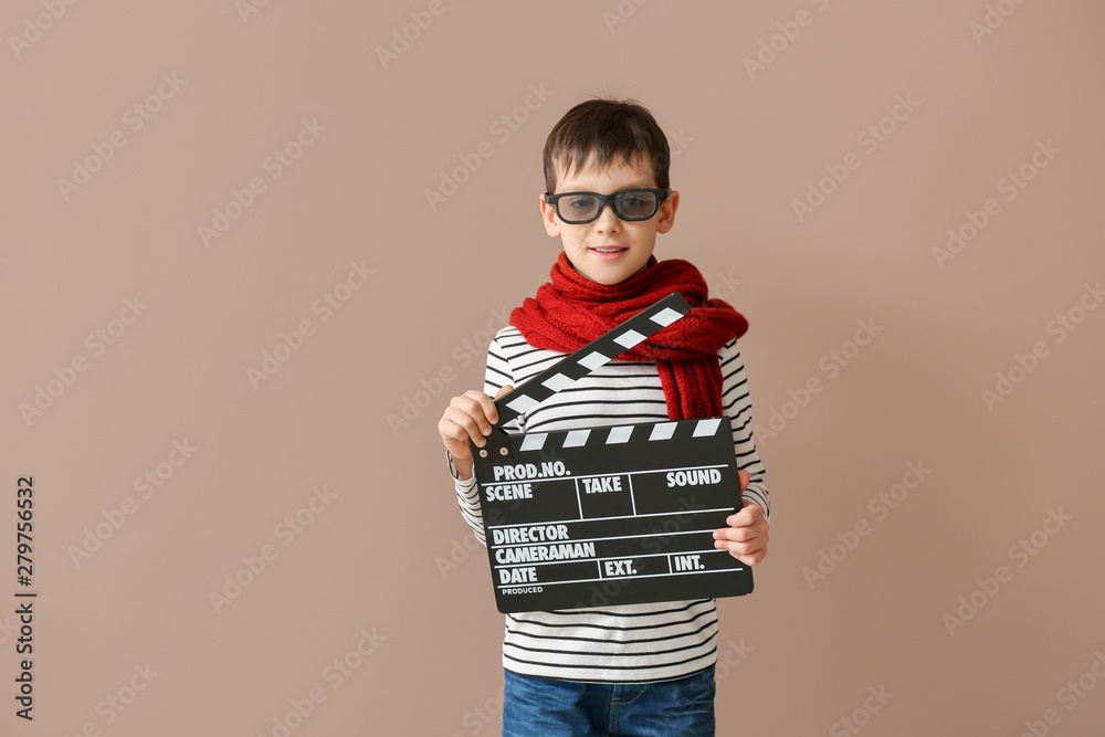 Little boy with clapperboard on color background