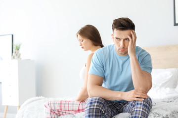 Poster - Upset young couple after quarrel sitting on bed