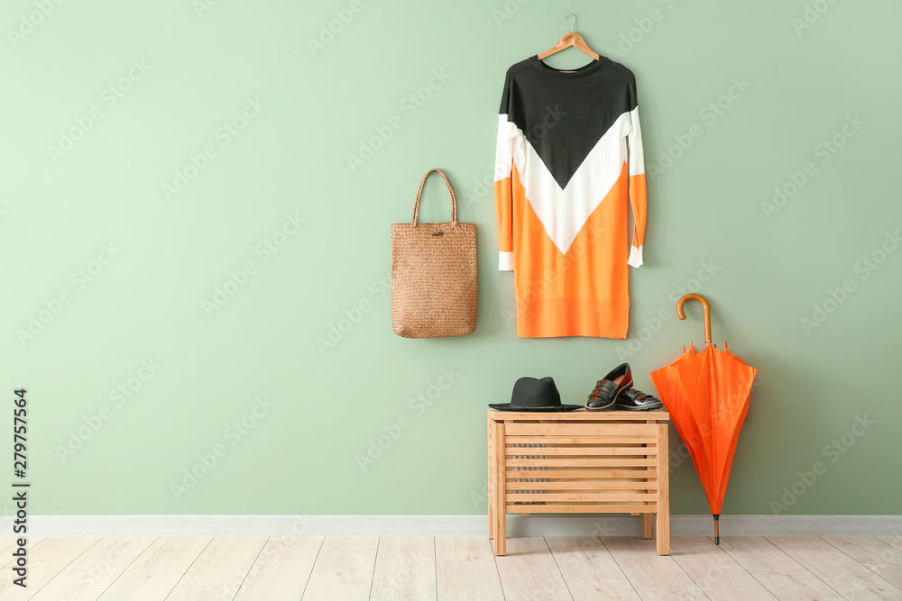 Stylish umbrella with clothes in interior of hall