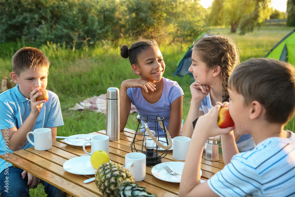 Group of children having picnic outdoors on summer day