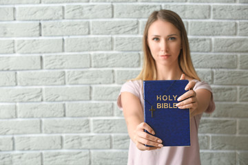 Wall Mural - Religious young woman with Bible against brick wall